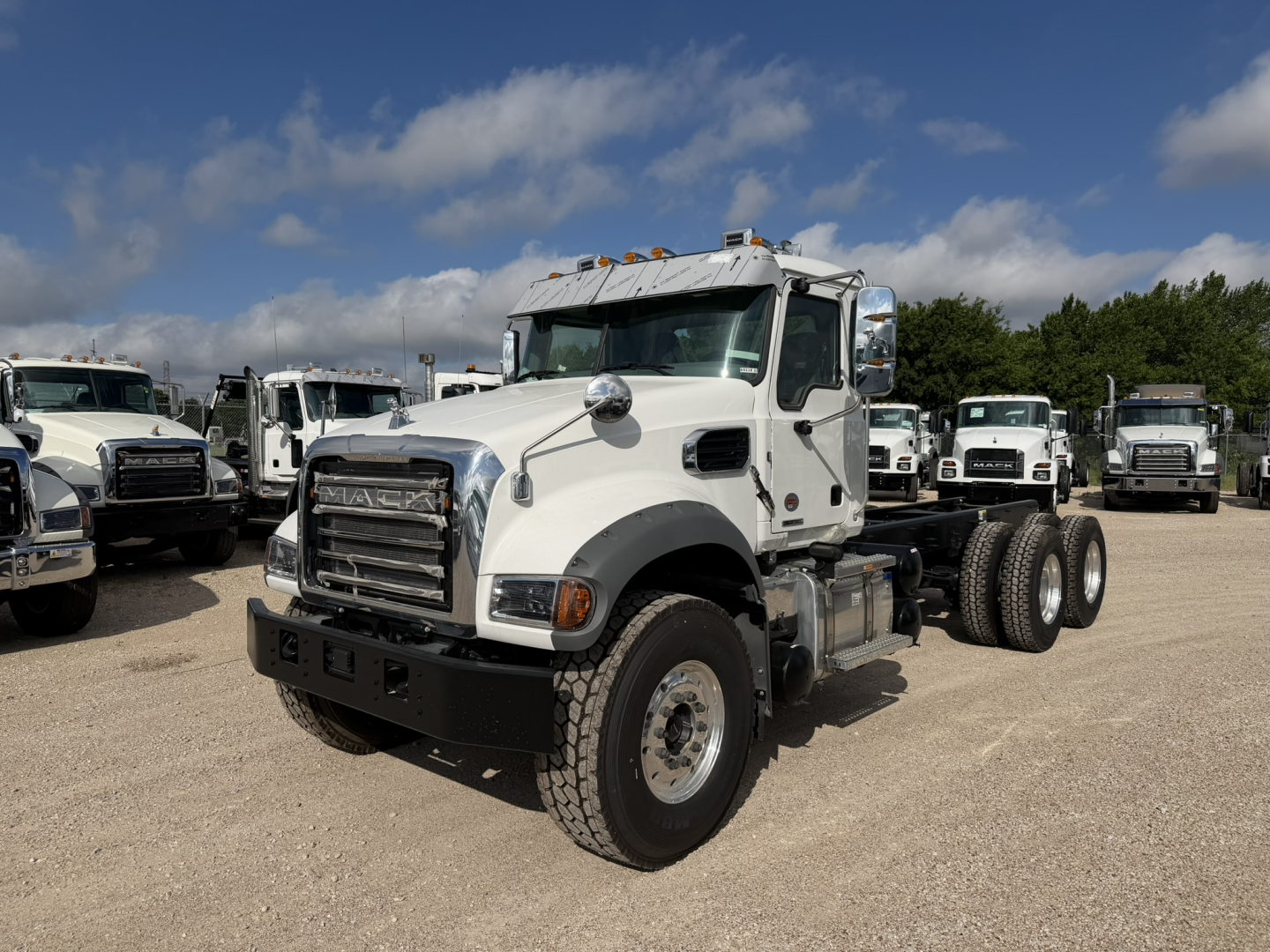 Mack GR64F cab and chassis truck in a dealership lot with other trucks in background.