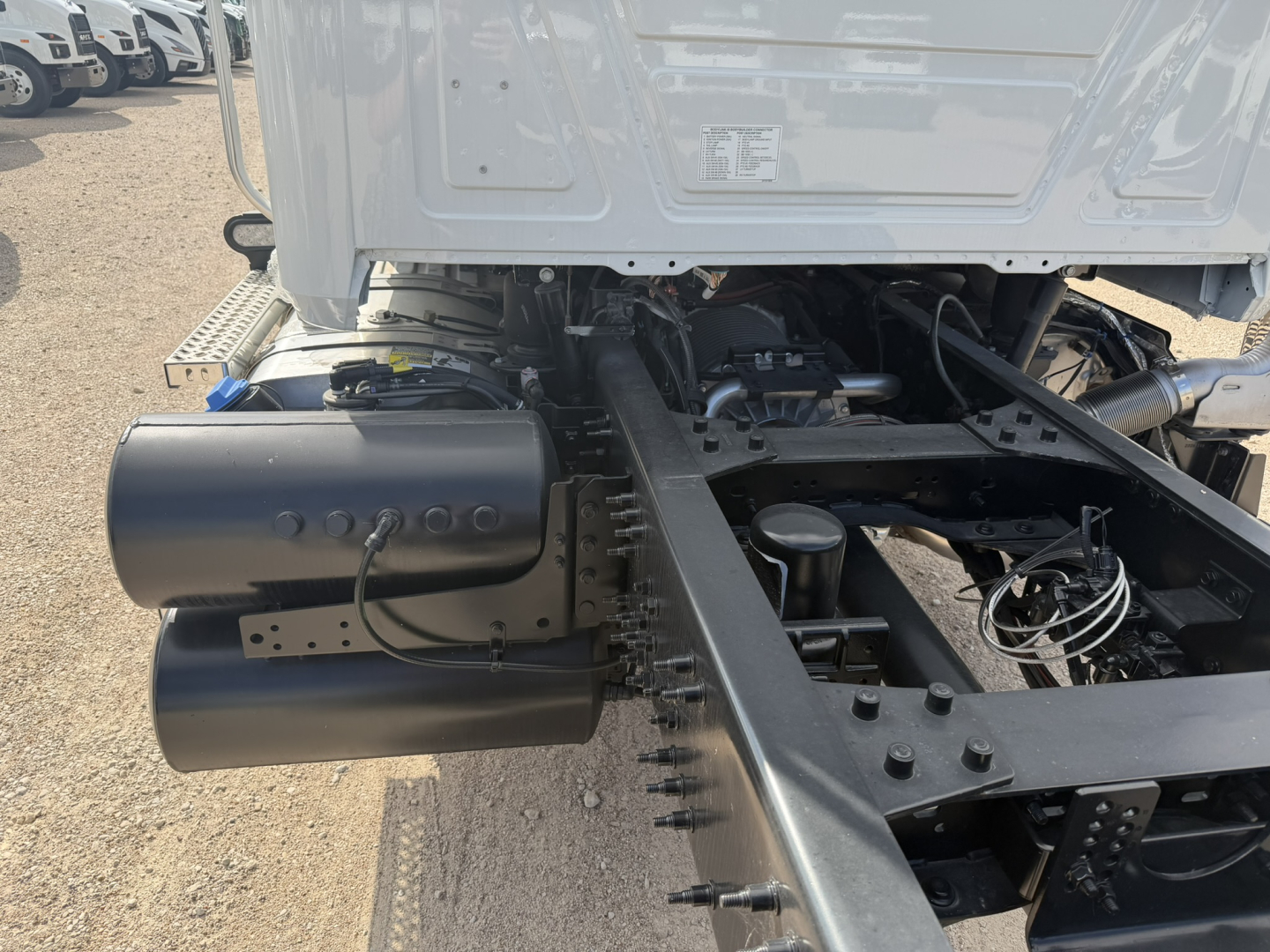 Truck chassis showing dual cylindrical fuel or air tanks mounted on the left side of the frame with a Mack GR64F cab and chassis area visible in background.