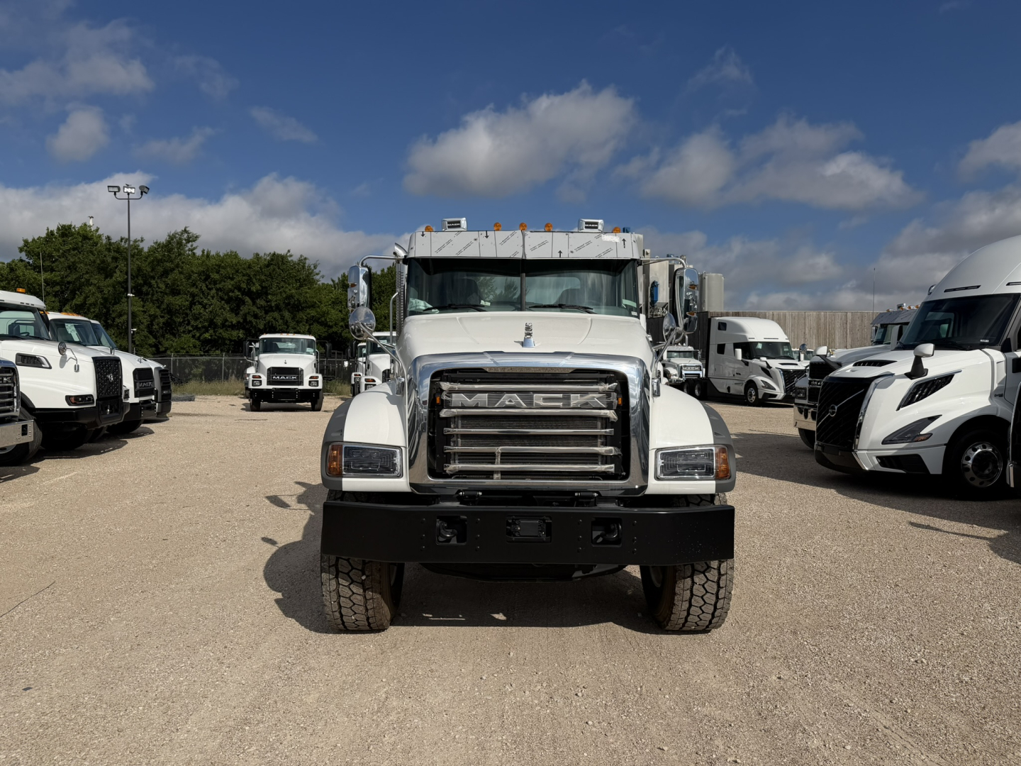Front view of a white 2026 Mack GR64F cab and chassis truck with large grille, bumper, and dual front tires visible.