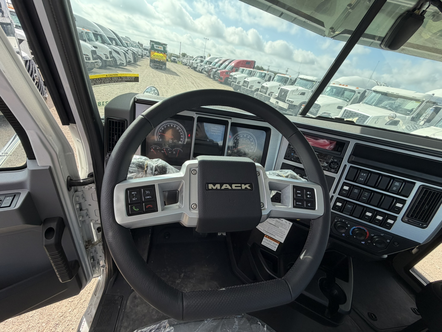 Steering wheel and dashboard of a 2026 Mack GR64F cab chassis showing Mack emblem on the steering wheel, instrument cluster, and center console panels.