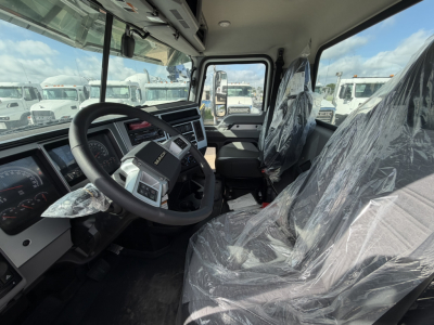 Cab interior of a 2026 Mack GR64F showing steering wheel, dashboard, and plastic-covered seats.