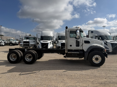 Truck chassis showing 3-axle Mack GR64F cab and chassis with empty bed and white cab.
