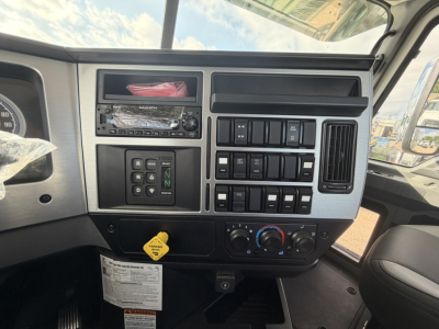 Cab and chassis dashboard of a 2026 Mack GR64F showing center stack with switches, ignition area, and climate controls.
