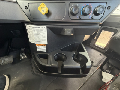 Mack GR64F cab interior showing control panel, ignition and dashboard, cup holders, and yellow engine stop/air switch label.