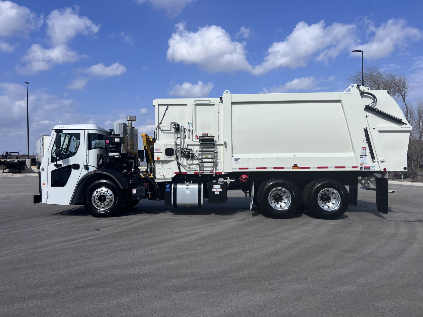 2026 Mack LR64 garbage truck side view showing cab and rear refuse body with hydraulic lift, aluminum chassis, dual rear axles, and side steps.