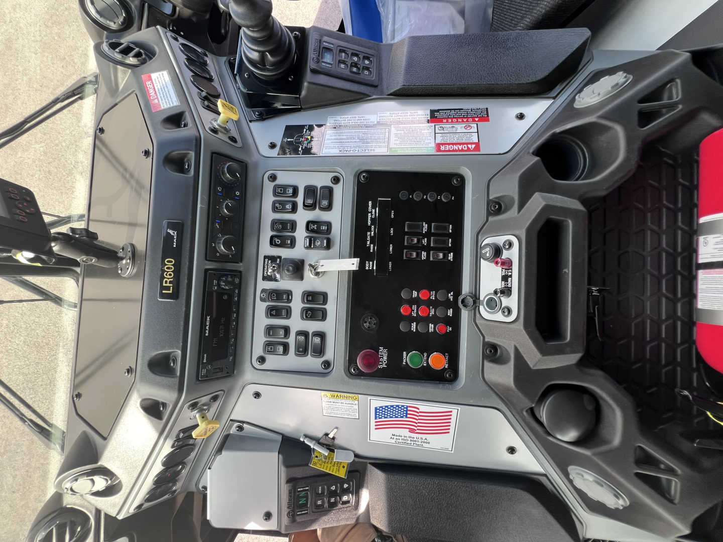 Mack LR64 console showing control panel with switches, gauges, and digital display; visible labels and switches in operator cockpit.