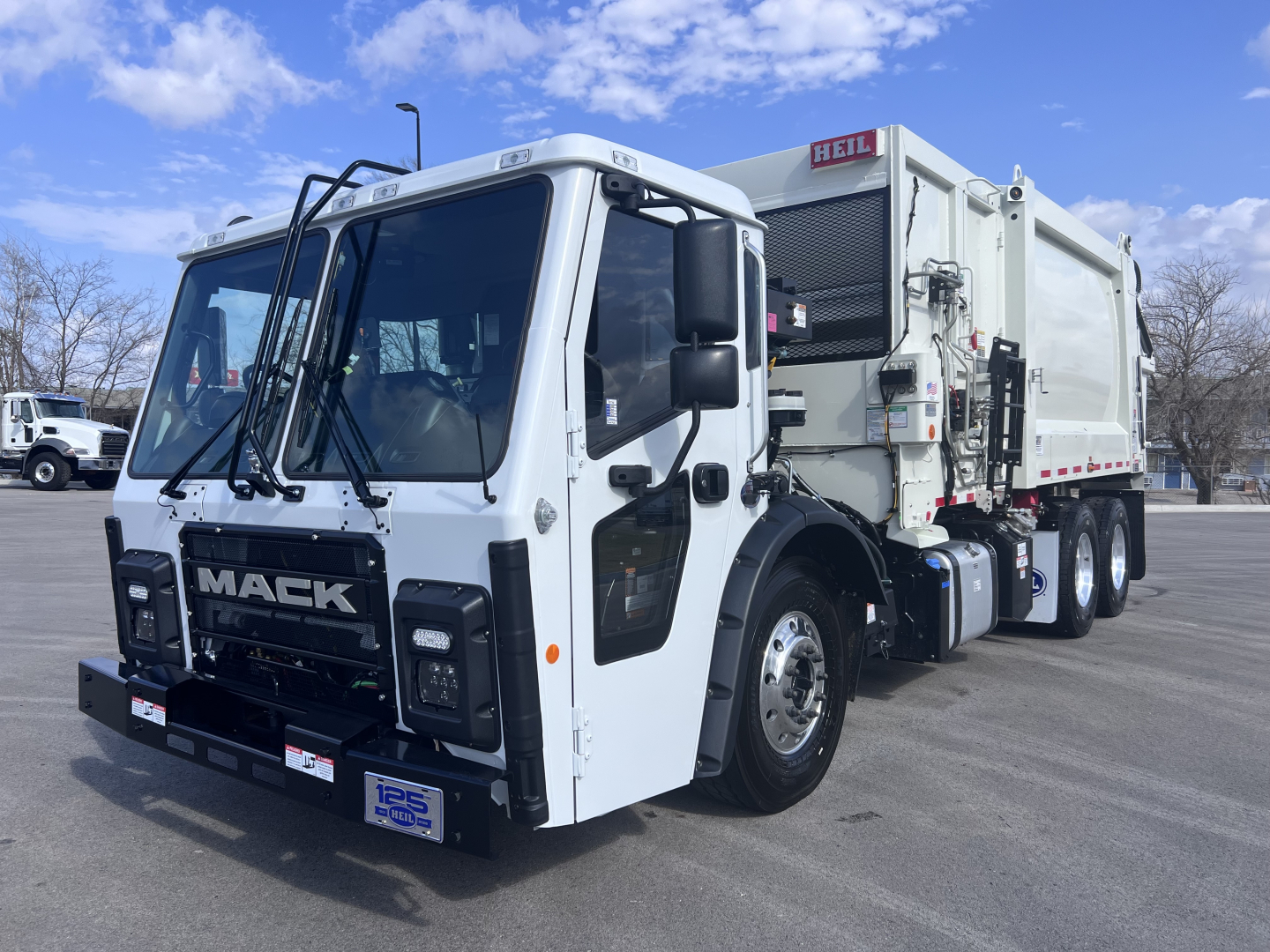 Garbage truck in white showing Mack LR cab and waste body with Heilig mixer label; front grille with MACK badge and large windshield.