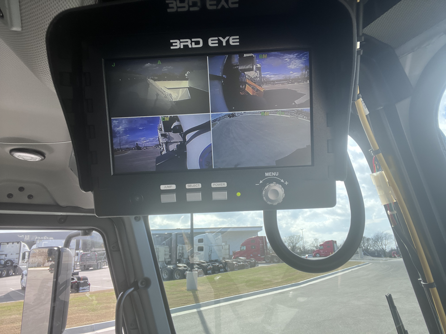 Cab interior showing 3rd Eye monitor with four camera feeds in a Mack LR64 truck, front windshield view, dashboard and control panel visible.