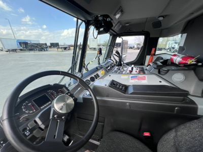 Cab interior of a 2026 Mack LR64 showing steering wheel, dashboard with gauges, pedals, and windshield view.