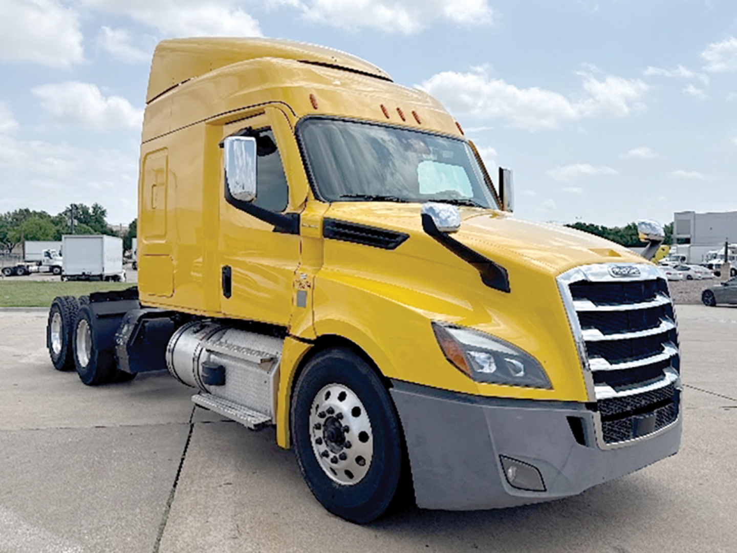 Yellow Freightliner Cascadia126 semi-truck cab in a parking lot, front three-quarter view showing grille, headlights, and sleeper cab.