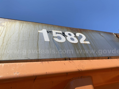 Container with the number 1582 on a blue-gray surface, viewed from the side with a rust-colored lower edge.