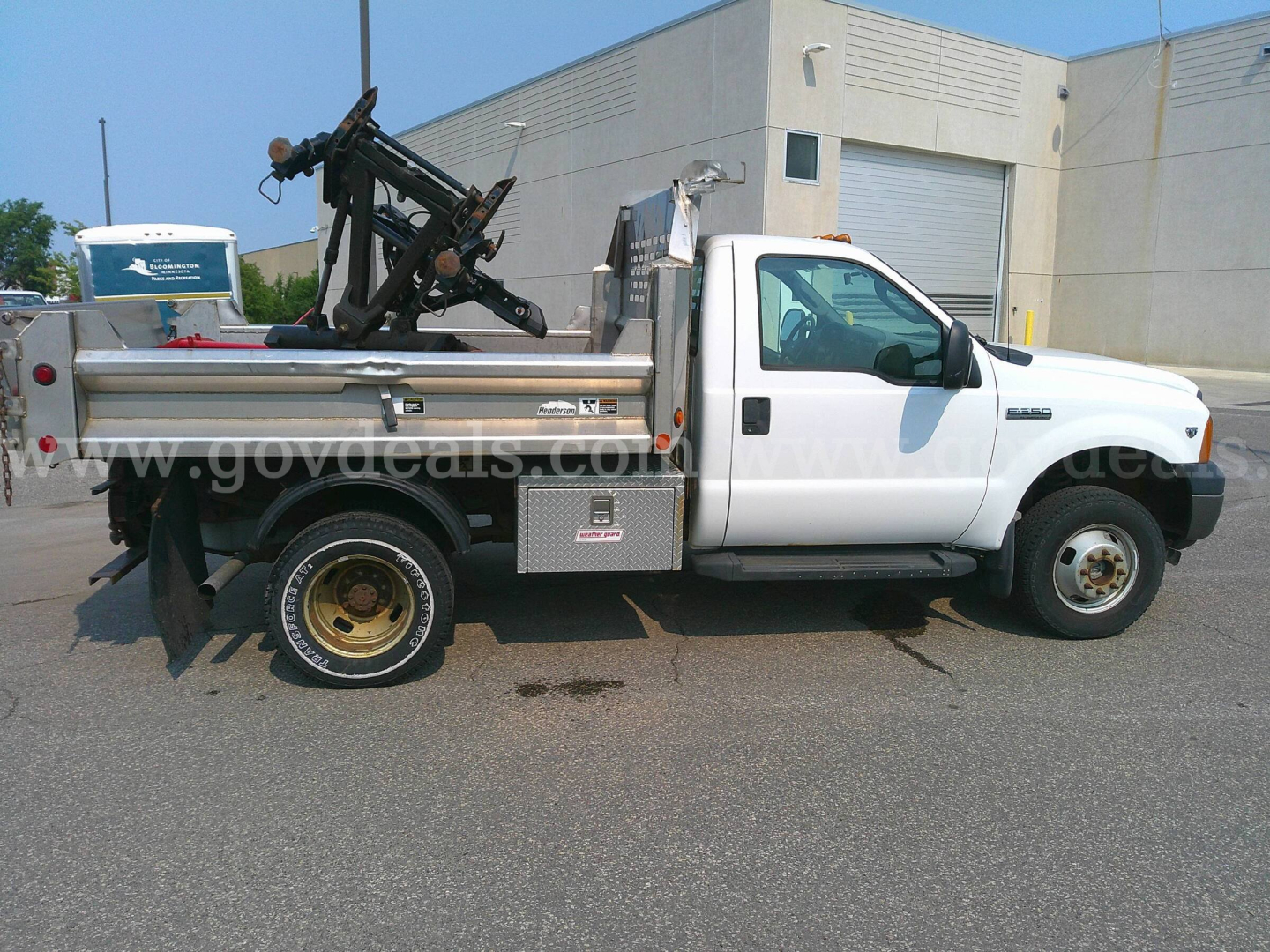 Ford F-350 dump truck in service showing utility bed with mounted hydraulic equipment and white cab.