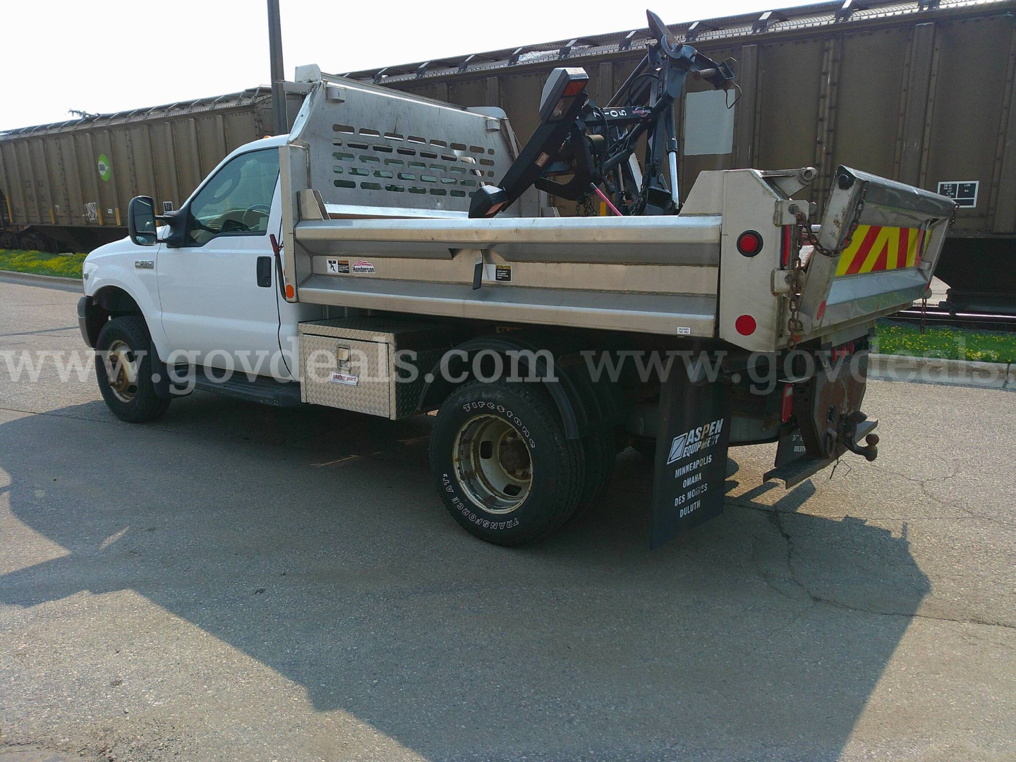 Ford F-350 dump truck side rear view showing dump bed and crane attachment.