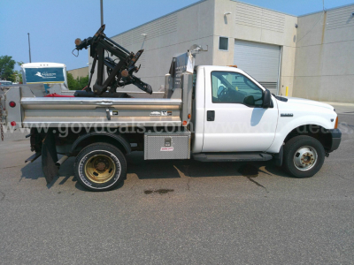 Ford F-350 dump truck in service showing utility bed with mounted hydraulic equipment and white cab.
