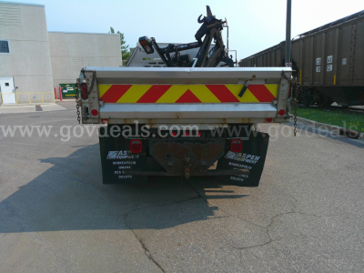 Truck bed in rear view showing reflective chevron pattern and hitch with back of dump truck attachment.