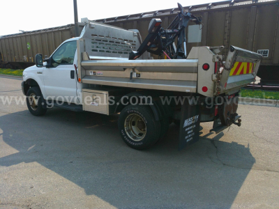 Ford F-350 dump truck side rear view showing dump bed and crane attachment.