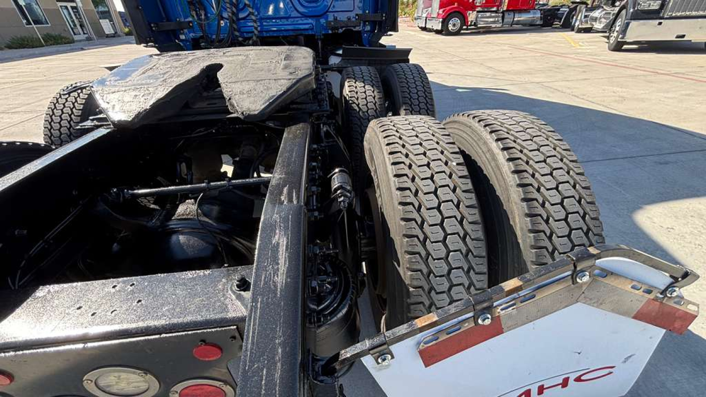 Truck chassis and dual rear axles showing suspension, frame, and fifth-wheel area with tires and landing gear in view.