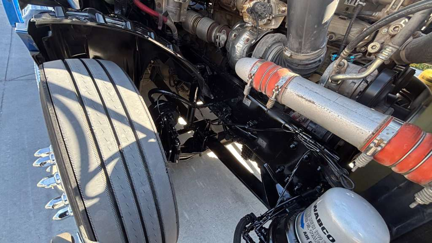 Freightliner PT126064ST chassis front view showing suspension and exhaust components with hose and piping.