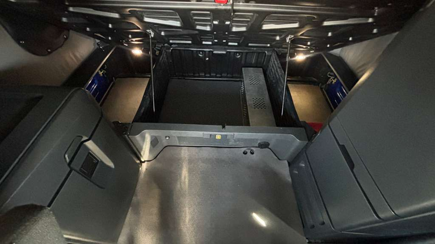 Freightliner PT126064ST sleeper cab interior cargo area with storage compartments and metal floor; low-angle view from rear cab hatch