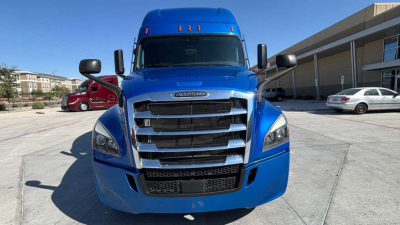 Blue Freightliner cab showing front grille, headlights, and bumper with chrome bars and badge visible.