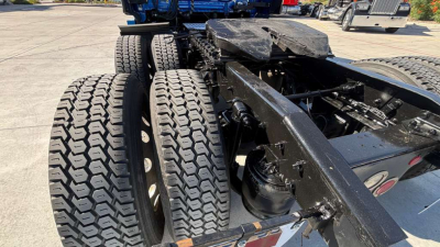 Truck chassis with dual rear axles and tires showing the undercarriage; visible components include the frame, suspension, and mounting points.
