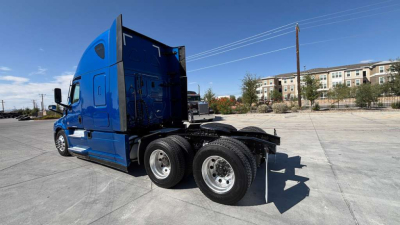 3/4 view of a blue Freightliner PT126064ST semi truck tractor showing side and rear wheels and sleeper cabin