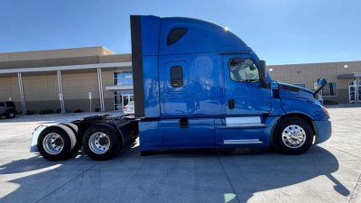 Truck side view showing blue Freightliner PT126064ST sleeper cab, single mid-window, dual rear axles, chrome wheels and 6x4 configuration.