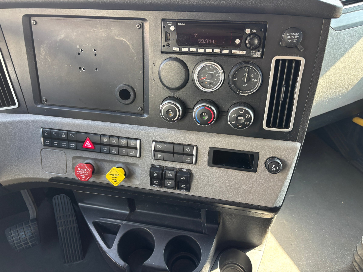 Dashboard of Freightliner PT126064ST truck showing gauge cluster, radio, climate controls, hazard button, and cup holders.