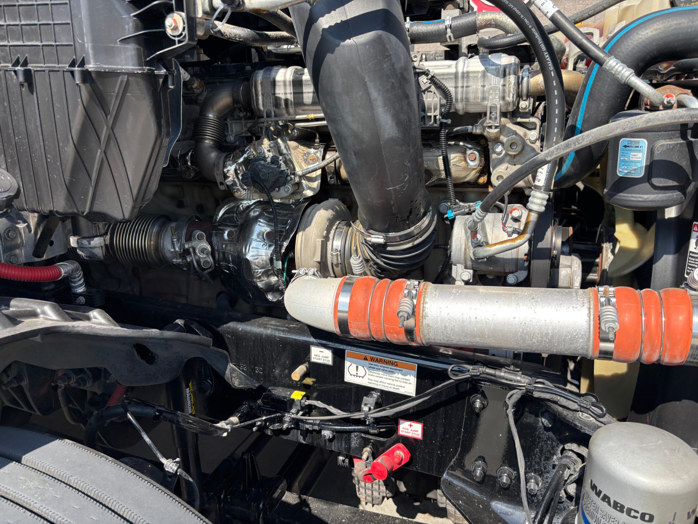 Freightliner PT126064ST engine bay showing coolant hoses, turbo piping, and various hoses with a red-handled valve; visible engine components and wiring.