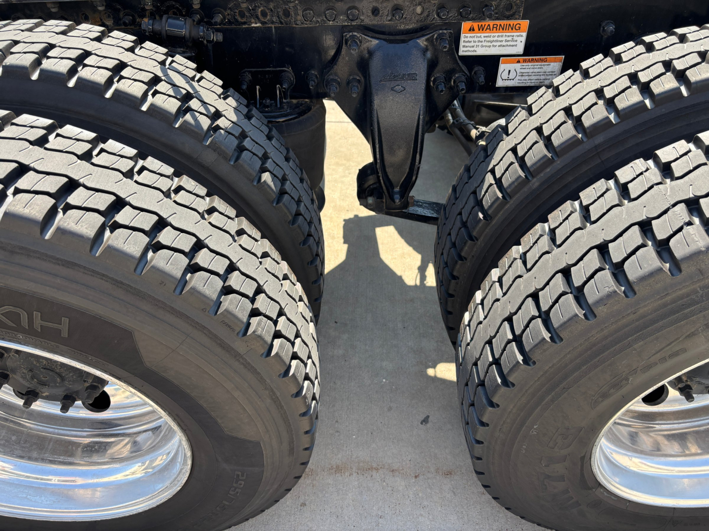 Dual rear trucks wheels and suspension of a Freightliner PT126064ST tractor showing twin tires and rear axle area with exposed chassis components.