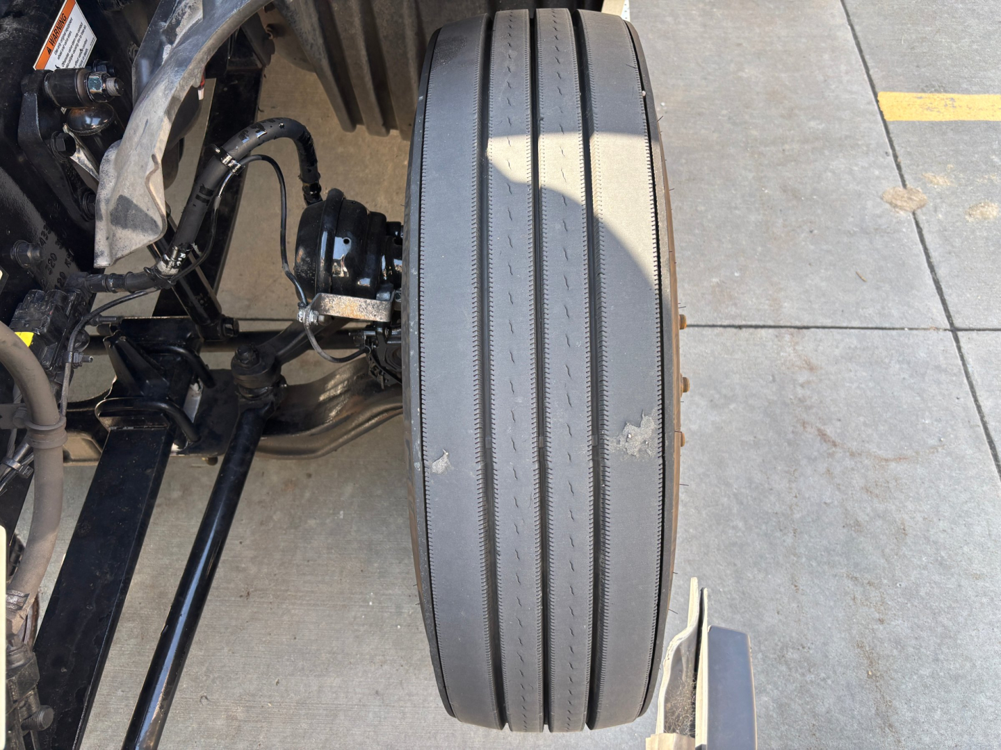 Airline-style single rear driven axle of a Freightliner truck showing heavily worn dual tires and surrounding suspension components.
