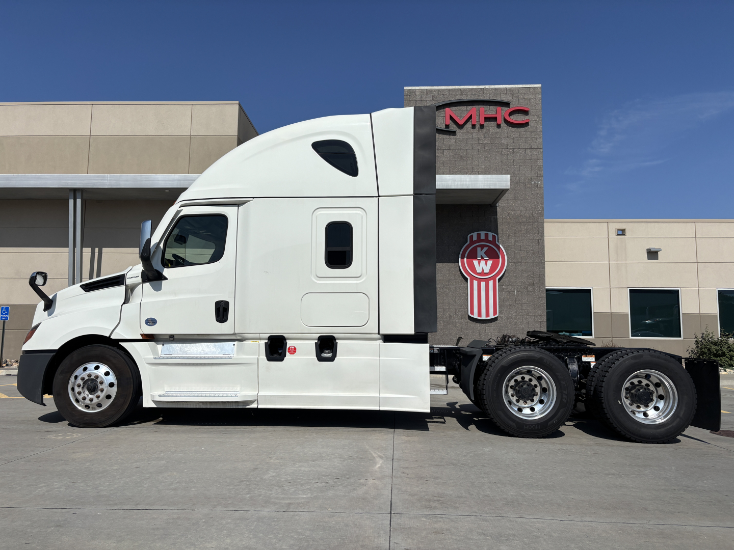 Truck side view showing white Freightliner PT126064ST sleeper cab and tandem rear axles.