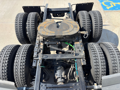 Tractor-trailer fifth wheel and chassis showing multiple axles and tires for a Freightliner PT126064ST in-service view with drivetrain and air hoses.