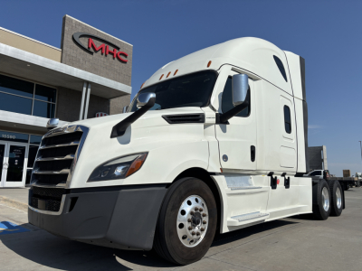 Truck: 2023 Freightliner PT126064ST semi-truck tractor in white, cab-forward view, with MHC dealership in background.