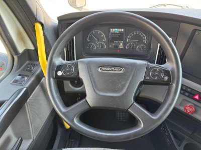 Steering wheel and dashboard of a Freightliner truck cab showing instrument cluster and controls.
