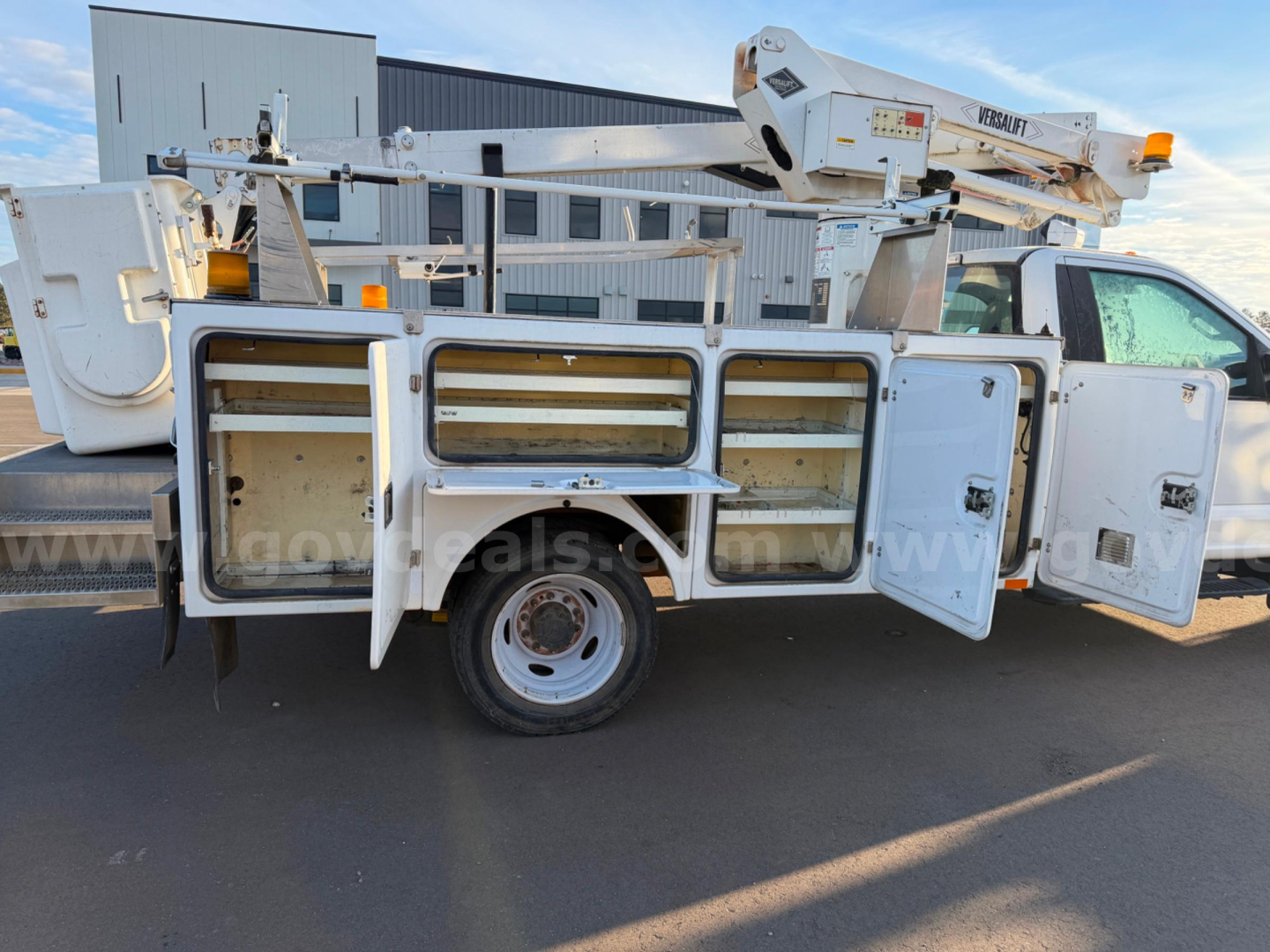 2018 Ford F550 bucket truck with service compartments open, visible tool/gear storage and utility body side view.