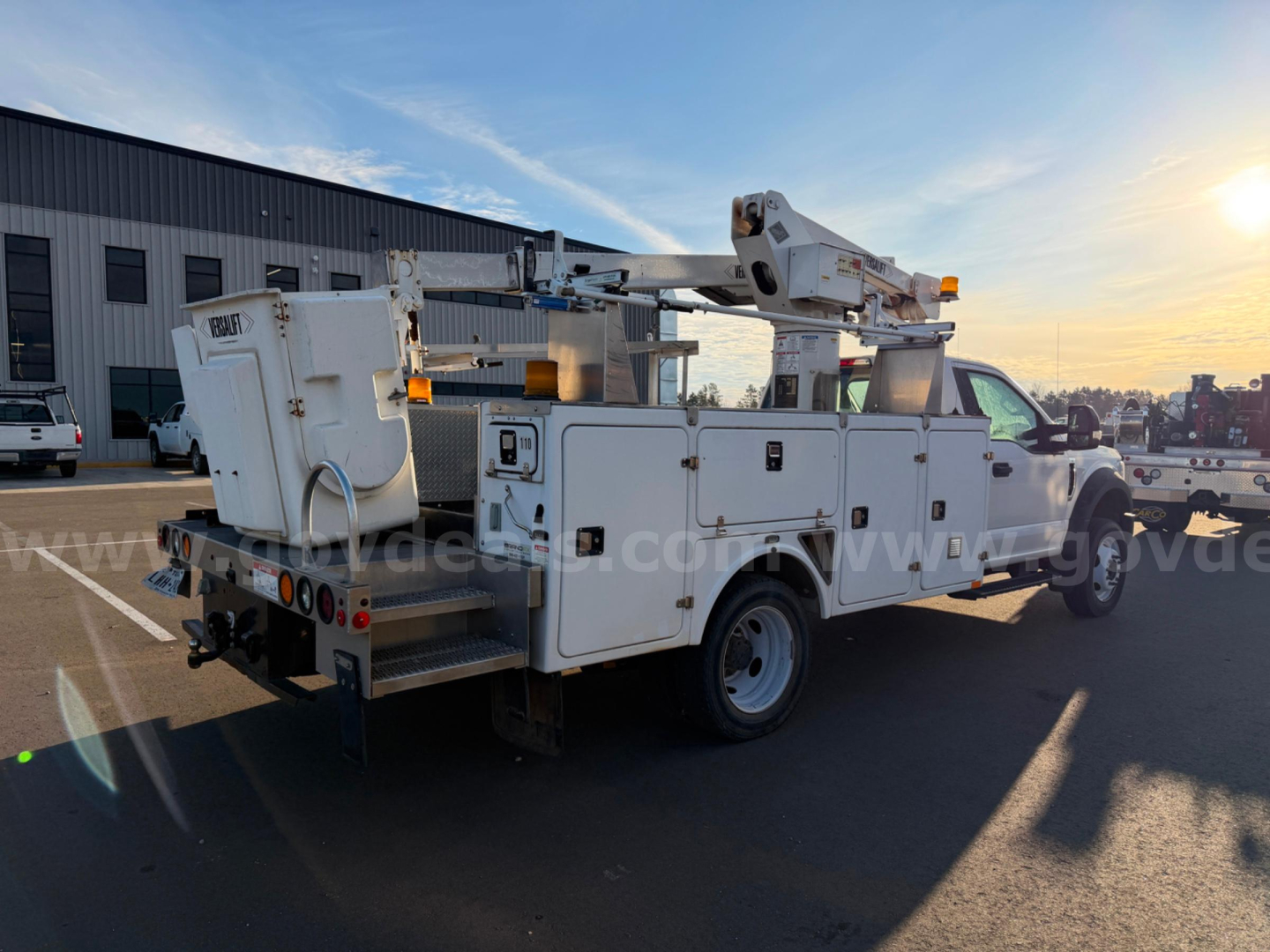 Ford F550 bucket truck in-service showing high-reach boom and service compartments, rear view with utility toolbox, 4x2 chassis, yellow clearance lights.