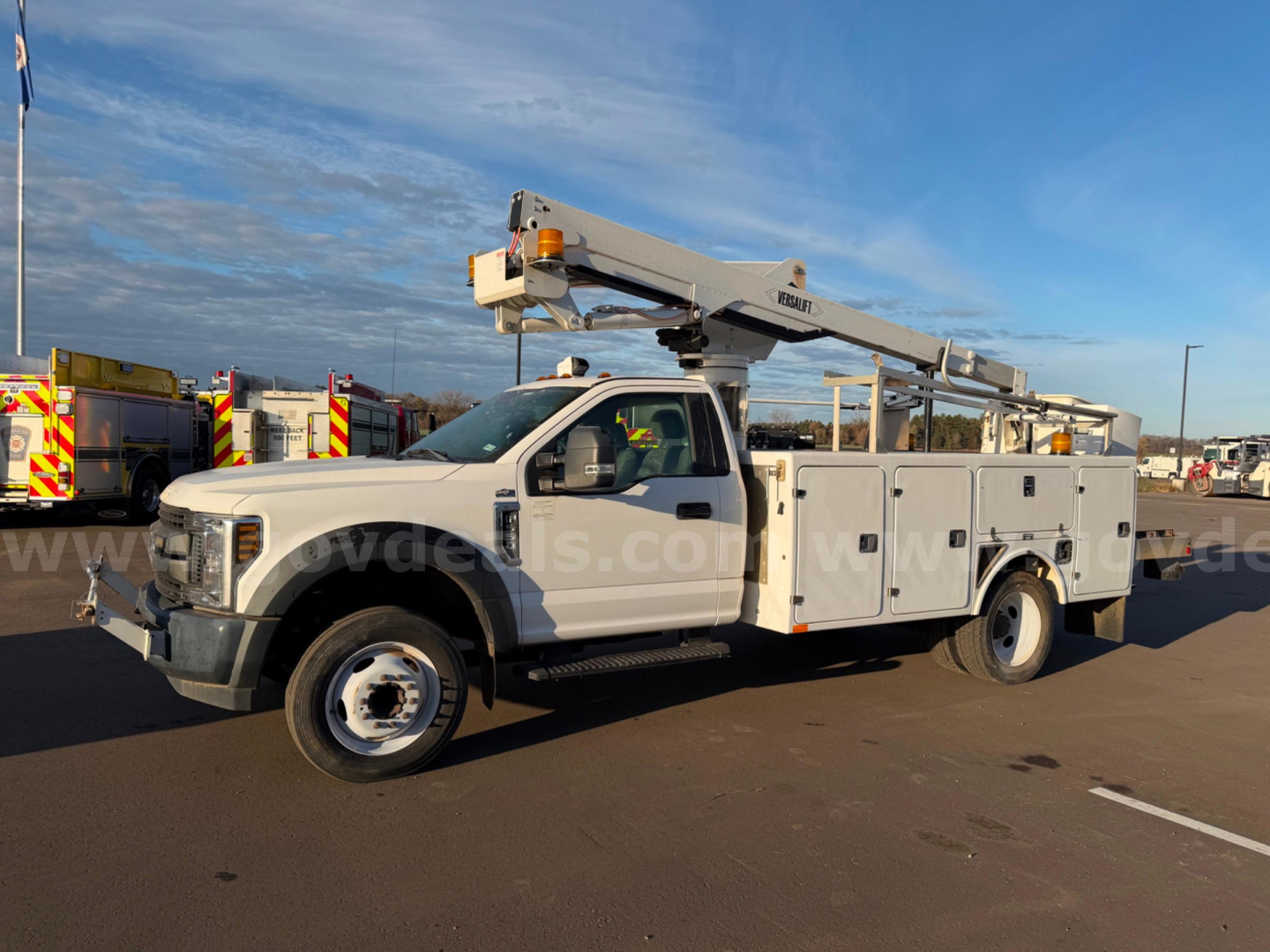 Ford F-550 bucket truck in-service showing utility bed with multiple compartments and a mounted boom lift on the chassis.