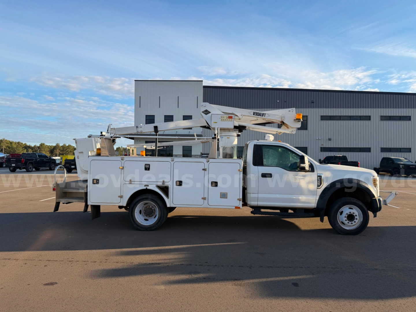 Ford F-550 bucket truck side view showing utility body and mounted boom lift.