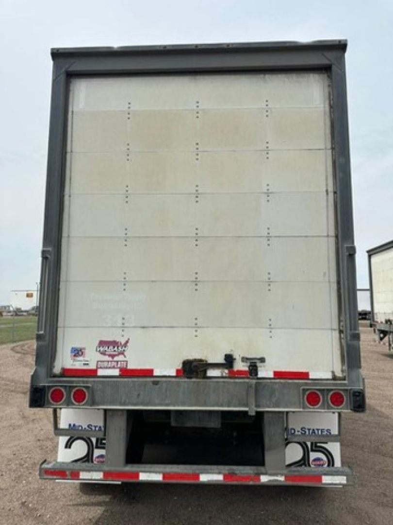 Rear view of a 2016 Wabash van trailer showing the rear doors and bumper with red and white reflective strips, small stickers near left, and taillights.