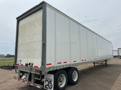 Trailer rear and side view showing tandem axle trailer with white aluminum sides and metal frame. Visible text includes number placards and rear bumper details.