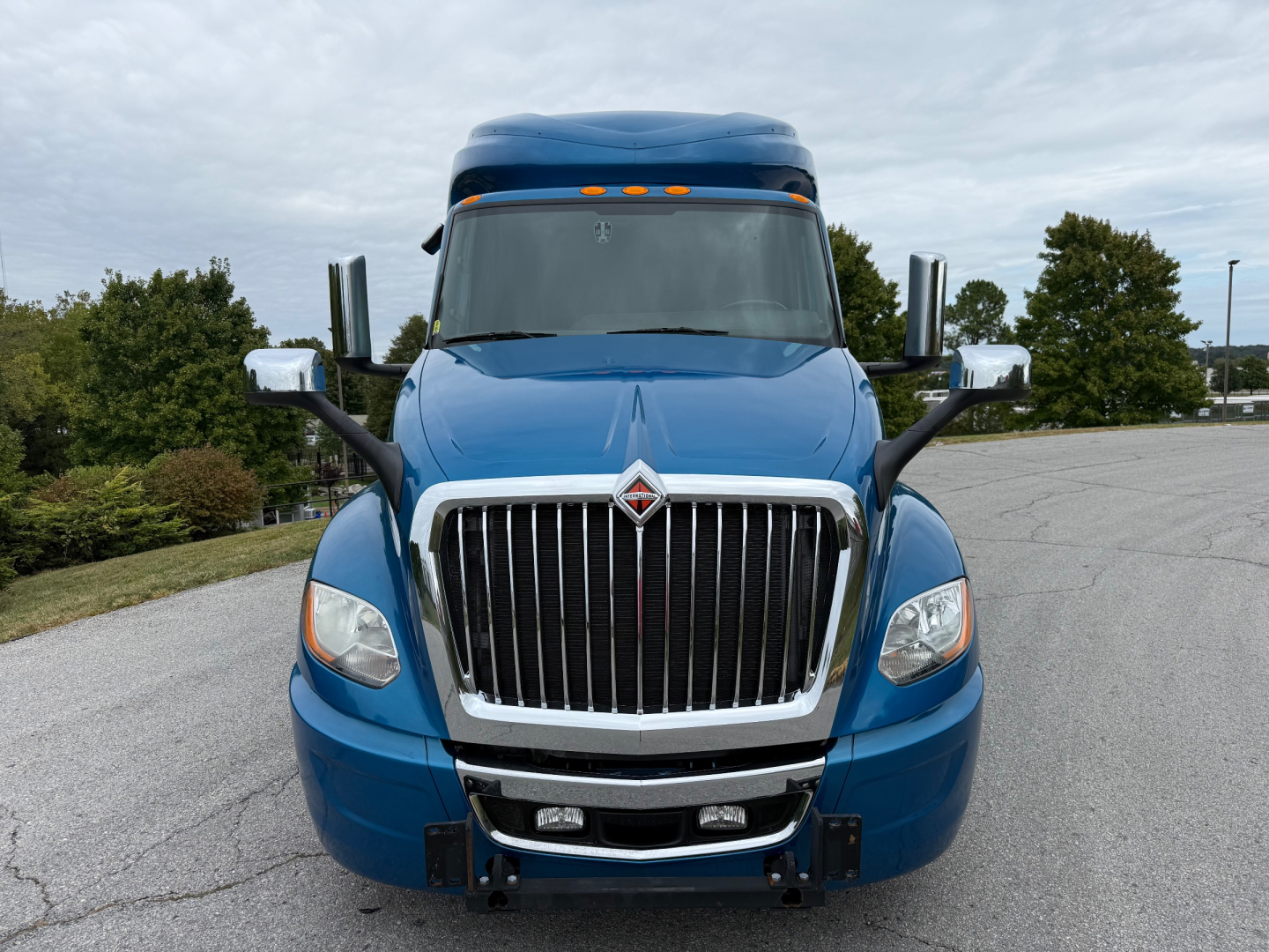 Front view of a blue 2024 International LT625 conventional sleeper truck showing chrome grille, bumper, and dual side mirrors.