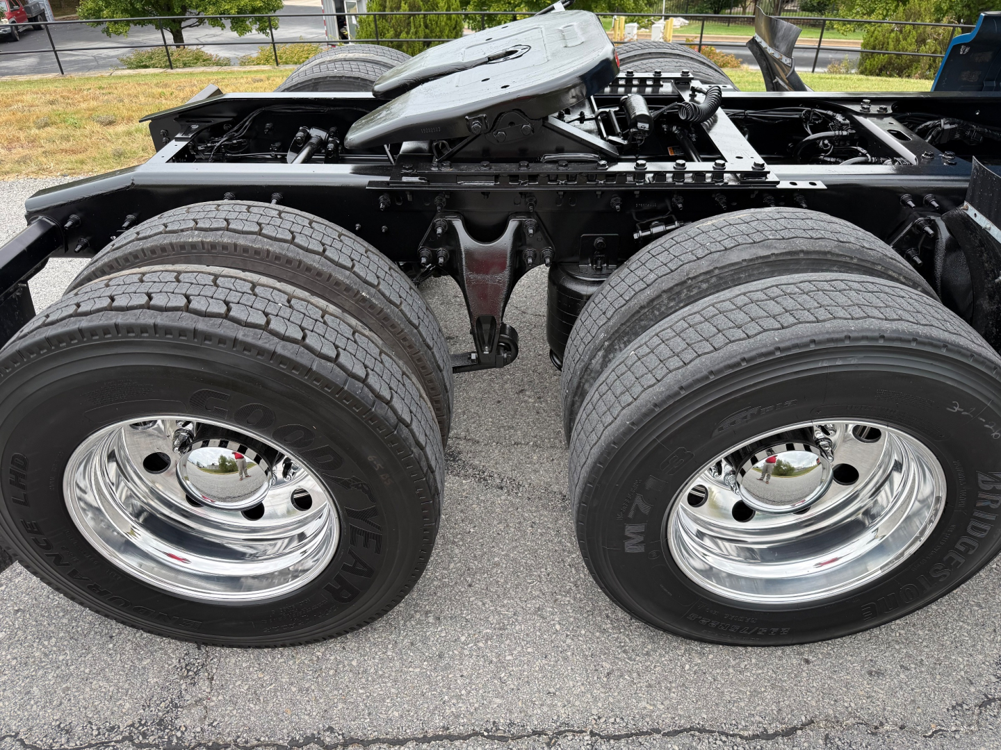 Truck chassis with dual rear axles and large tires; chassis frame and air tanks visible under cab.