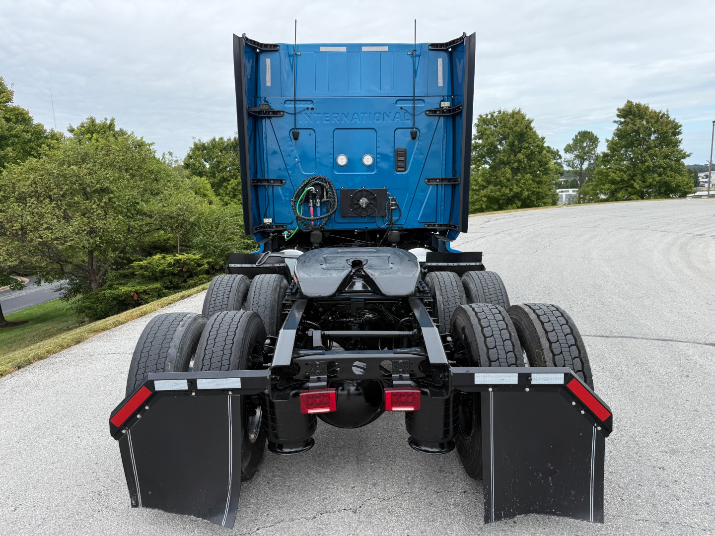 Truck chassis rear view showing dual rear axles, fifth-wheel plate, and mud flaps on a blue cab unit.