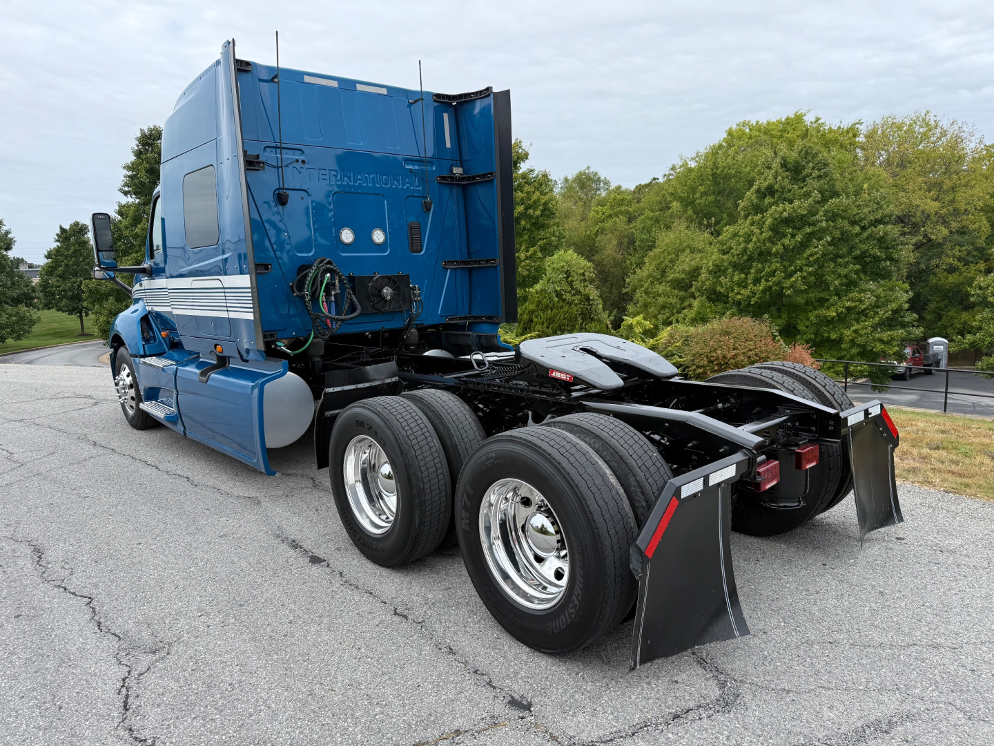 Truck chassis and rear cab of a blue 2024 International LT625 tractor showing dual rear axles and mud flaps.