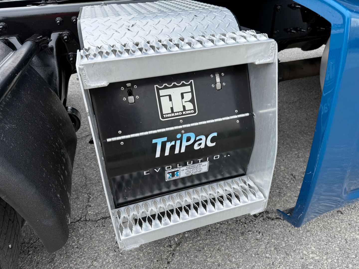 Semi truck side view showing TriPac Evolution auxiliary power unit with Diamond plate steps and Thermo King emblem.