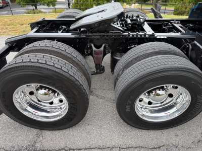 Truck chassis with dual rear axles and large tires; chassis frame and air tanks visible under cab.