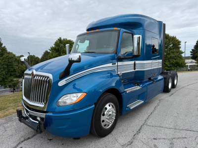 Blue 2024 International LT625 conventional sleeper truck with streamlined cab and chrome grille, showing side view and front wheel.