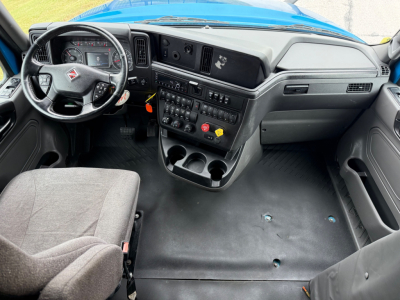 Interior cockpit of a 2024 International LT625 truck showing steering wheel, dashboard, and center console with controls and cup holders.
