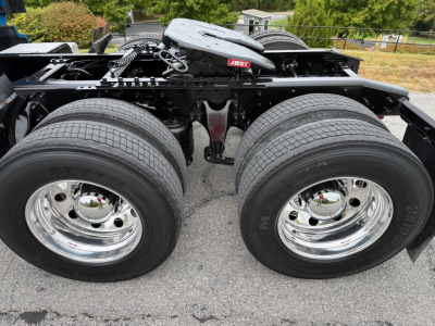Dual rear axles with chrome wheels and tires, International LT625 chassis visible, label and components on top rail; no visible text legible except tire branding. View focuses on rear wheel area and frame.